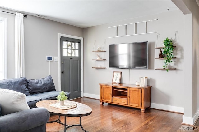 living room with visible vents, baseboards, and wood finished floors