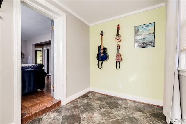 corridor featuring crown molding, stone finish floor, and baseboards