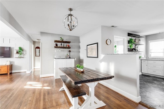 dining space featuring wood finished floors, visible vents, arched walkways, and baseboards