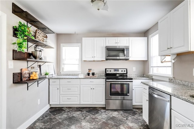 kitchen with light stone counters, baseboards, open shelves, stainless steel appliances, and white cabinetry