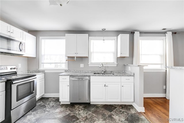 kitchen with white cabinetry, stainless steel appliances, baseboards, and a sink