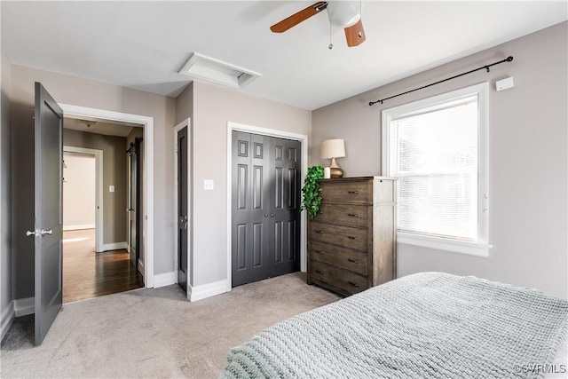 carpeted bedroom with a ceiling fan, attic access, baseboards, and a closet