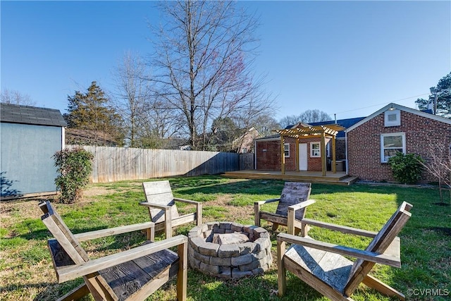 view of yard with an outbuilding, fence, a fire pit, a storage shed, and a wooden deck