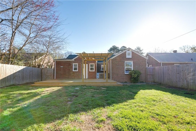 rear view of property with a deck, a fenced backyard, a pergola, and brick siding