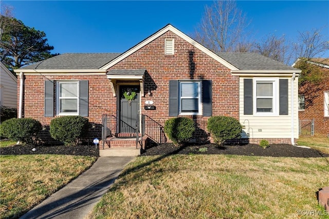 bungalow-style home featuring brick siding, a front lawn, and roof with shingles