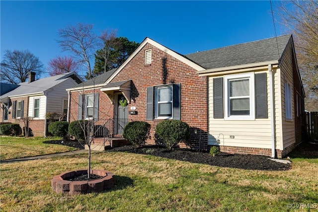 bungalow-style home with brick siding, a shingled roof, and a front yard