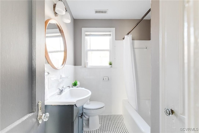 full bathroom with vanity, visible vents, tile walls, toilet, and shower / tub combo with curtain