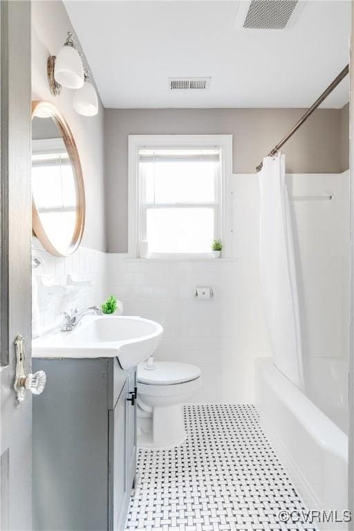 full bathroom featuring vanity, tile walls, toilet, and visible vents