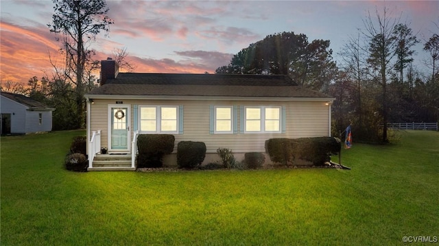 back of property featuring a lawn, a chimney, and fence