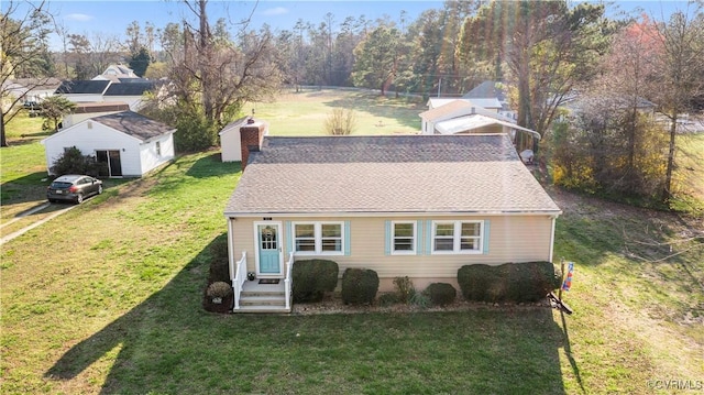 view of front facade with a shingled roof, a front yard, entry steps, and a chimney