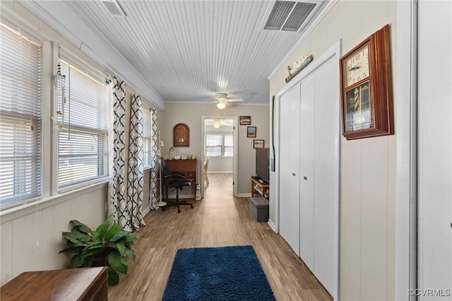 corridor featuring crown molding, plenty of natural light, visible vents, and light wood finished floors