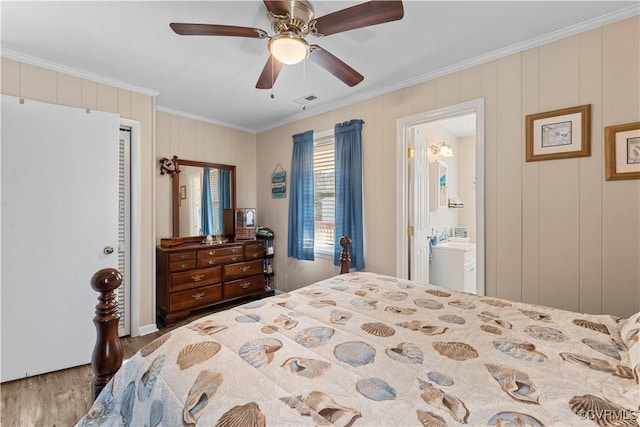 bedroom with wood finished floors, visible vents, ensuite bath, ceiling fan, and ornamental molding