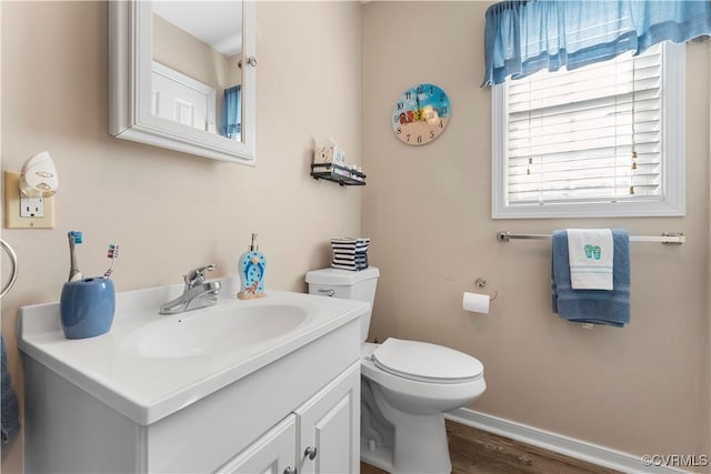 bathroom with baseboards, toilet, wood finished floors, and vanity