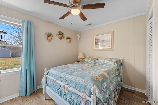 bedroom featuring visible vents, ornamental molding, baseboards, and wood finished floors