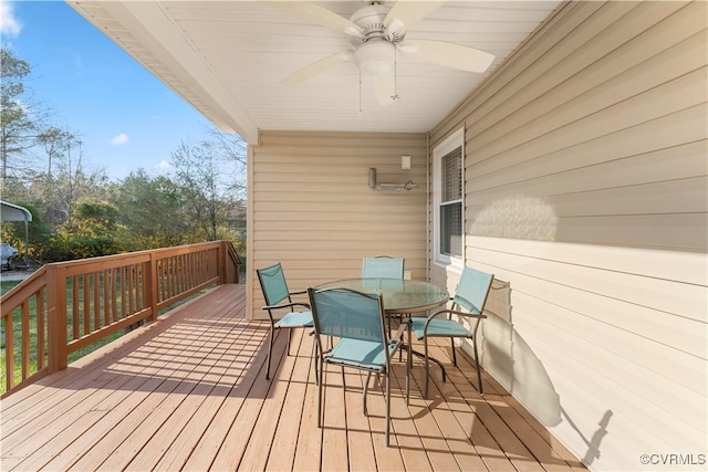 wooden terrace with outdoor dining area and a ceiling fan