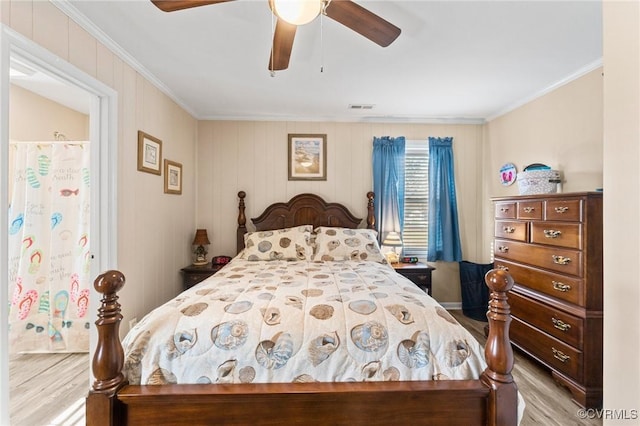 bedroom with ceiling fan, visible vents, wood finished floors, and ornamental molding