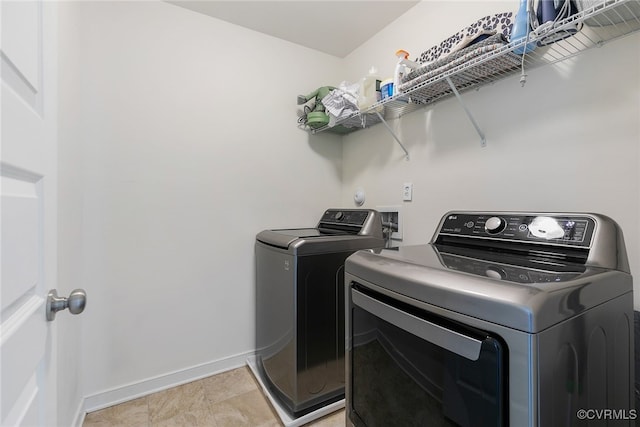 clothes washing area featuring laundry area, baseboards, and washing machine and clothes dryer