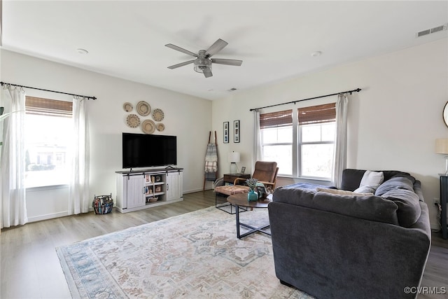 living area featuring visible vents, baseboards, a ceiling fan, and wood finished floors