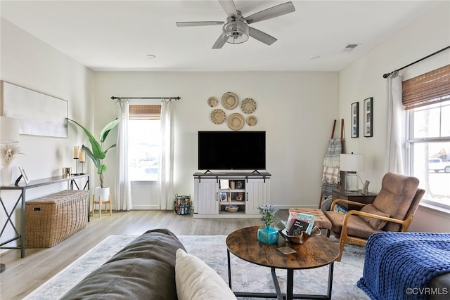 living room featuring plenty of natural light, a ceiling fan, visible vents, and wood finished floors