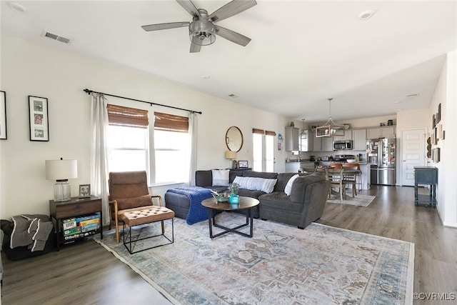 living area featuring visible vents, ceiling fan, and wood finished floors