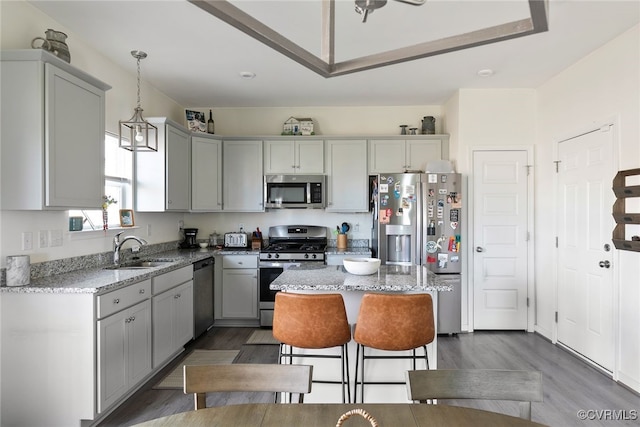 kitchen with a sink, stainless steel appliances, light stone countertops, and gray cabinets