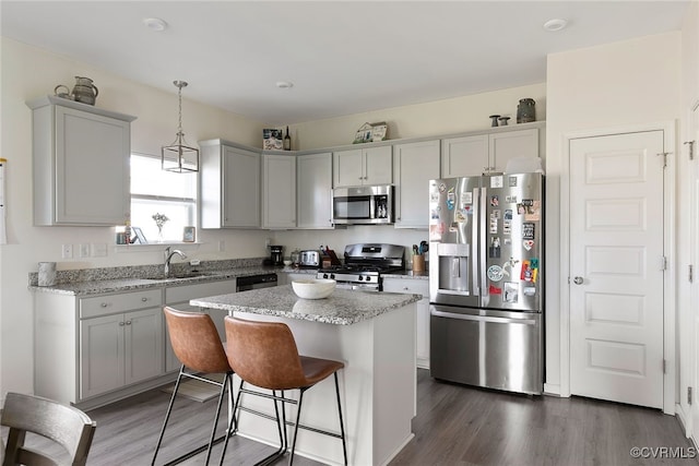 kitchen featuring a kitchen island, a kitchen breakfast bar, dark wood-style floors, stainless steel appliances, and a sink