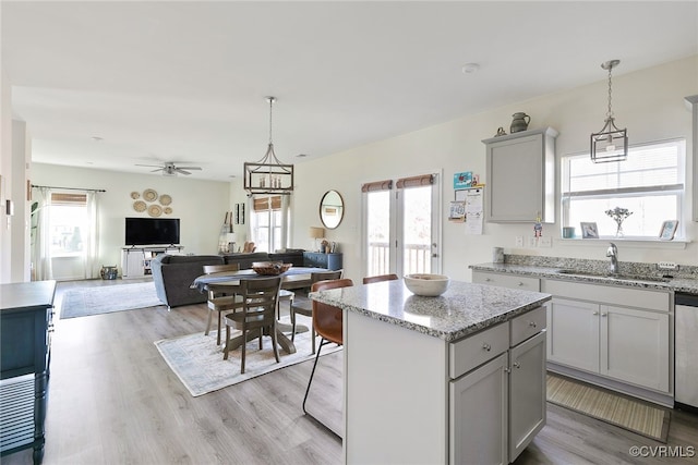 kitchen featuring light wood finished floors, pendant lighting, a center island, and a sink