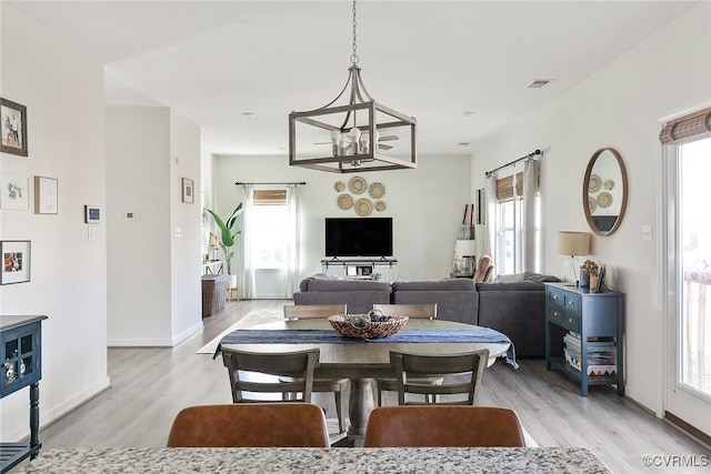 dining area featuring light wood-style floors, visible vents, a chandelier, and baseboards