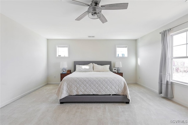 bedroom featuring visible vents, light colored carpet, baseboards, and ceiling fan