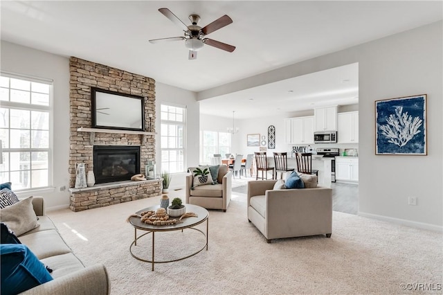 living room featuring ceiling fan, a fireplace, baseboards, and light carpet