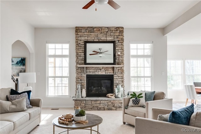 carpeted living area with baseboards, a fireplace, visible vents, and ceiling fan