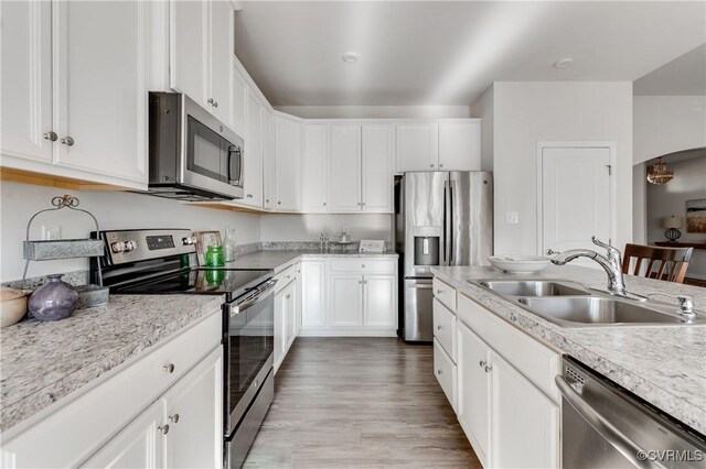 kitchen with appliances with stainless steel finishes, white cabinetry, light countertops, and a sink