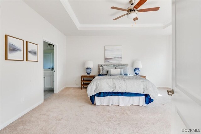 bedroom with a tray ceiling, connected bathroom, carpet, baseboards, and ceiling fan