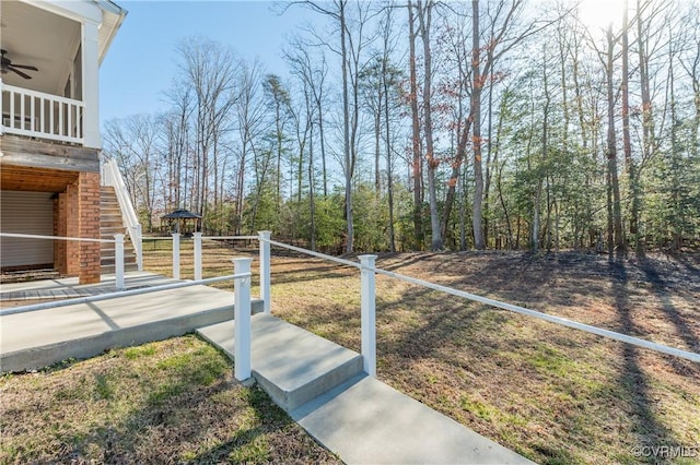 view of yard featuring stairway, ceiling fan, and fence