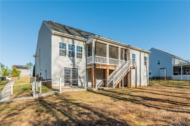 rear view of house featuring a patio, fence, a lawn, and a sunroom