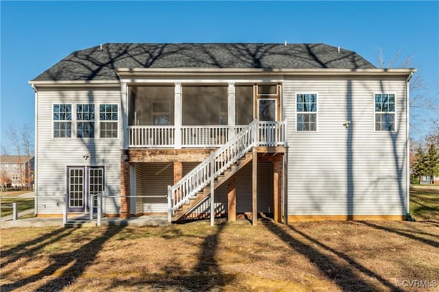 rear view of property featuring a lawn, stairs, and a sunroom