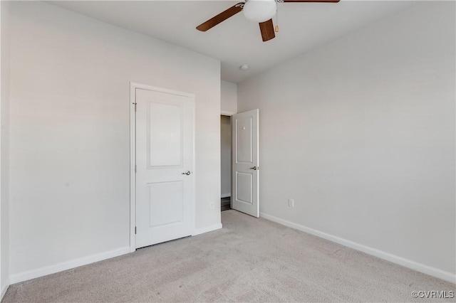 unfurnished bedroom featuring light colored carpet, a ceiling fan, and baseboards