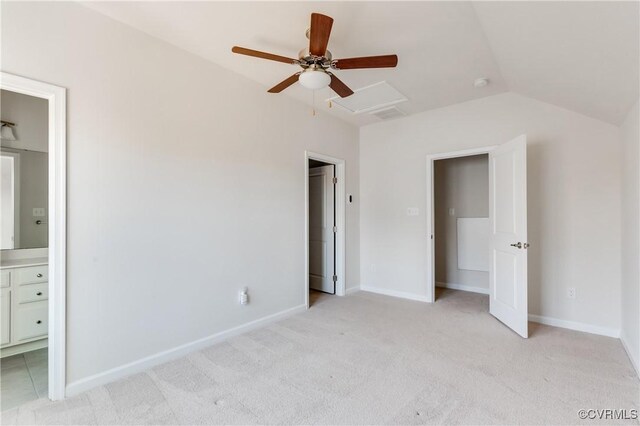 unfurnished bedroom featuring lofted ceiling, a ceiling fan, ensuite bath, baseboards, and light colored carpet