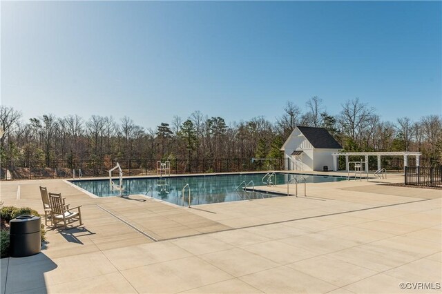 community pool featuring a patio, an outbuilding, and fence