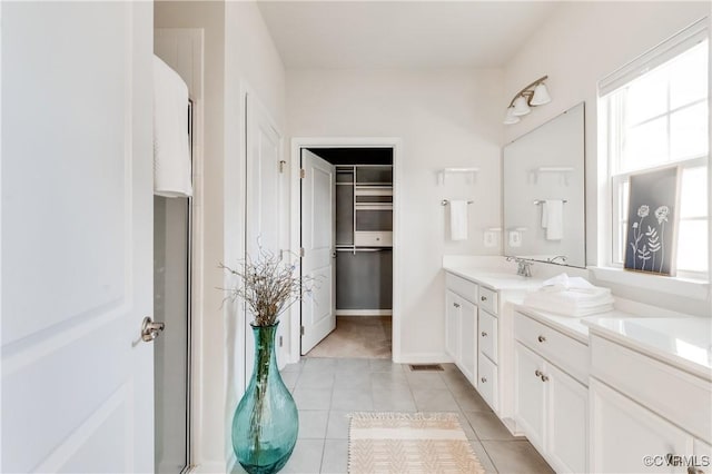 bathroom with visible vents, a walk in closet, a shower with shower door, tile patterned floors, and vanity