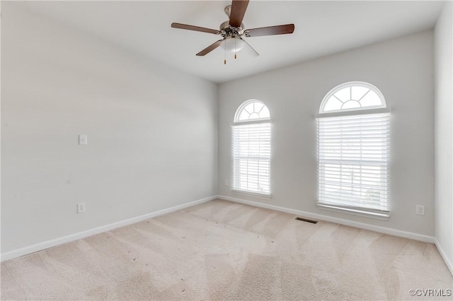 carpeted empty room featuring visible vents, baseboards, and ceiling fan