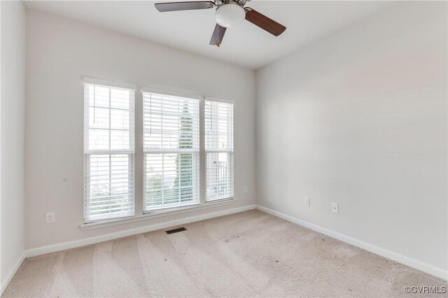 empty room with baseboards, visible vents, carpet floors, and ceiling fan