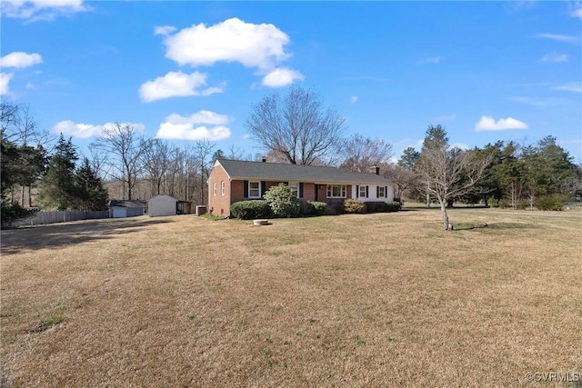 ranch-style house featuring fence, a front lawn, an outdoor structure, a storage unit, and brick siding