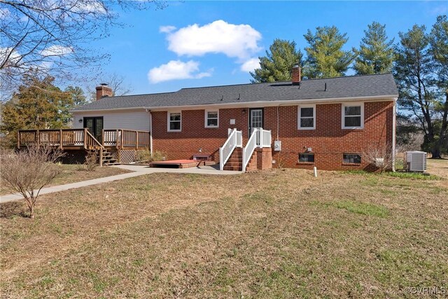 rear view of property with brick siding, a chimney, and central AC