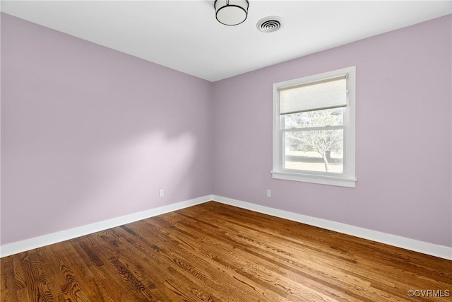 unfurnished room featuring visible vents, baseboards, and wood finished floors