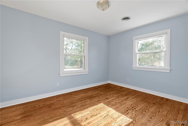 empty room featuring visible vents, baseboards, and wood finished floors