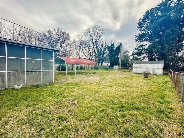 view of yard with a carport, an outdoor structure, and fence