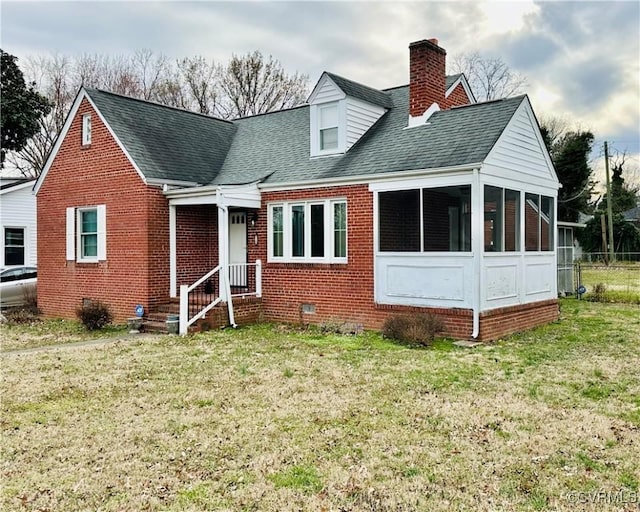 cape cod house with brick siding, a front lawn, roof with shingles, a chimney, and a sunroom