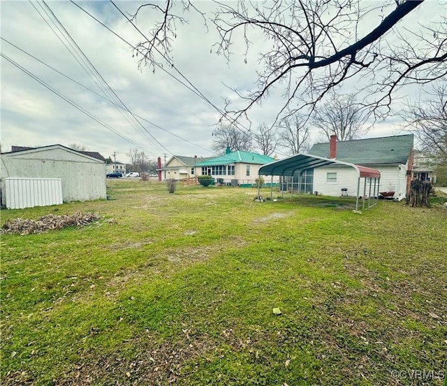 view of yard with a detached carport, an outdoor structure, and driveway