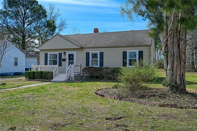 view of front facade with a chimney, a front lawn, and a shingled roof